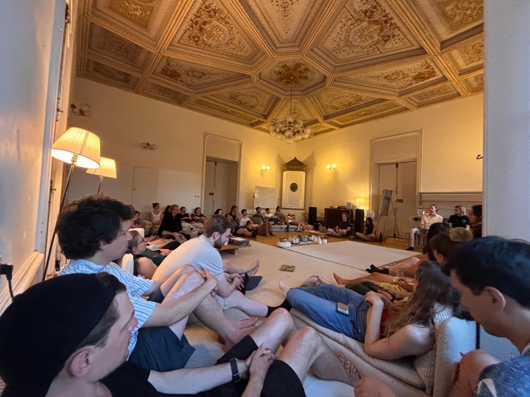 A circle of people under a frescoed ceiling